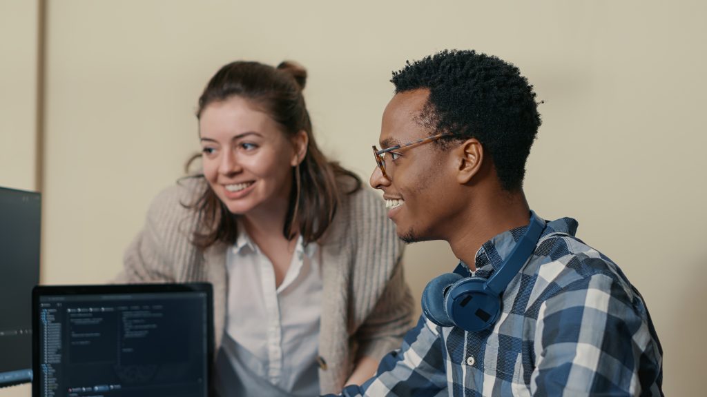 Two people having a discussion in front of a laptop