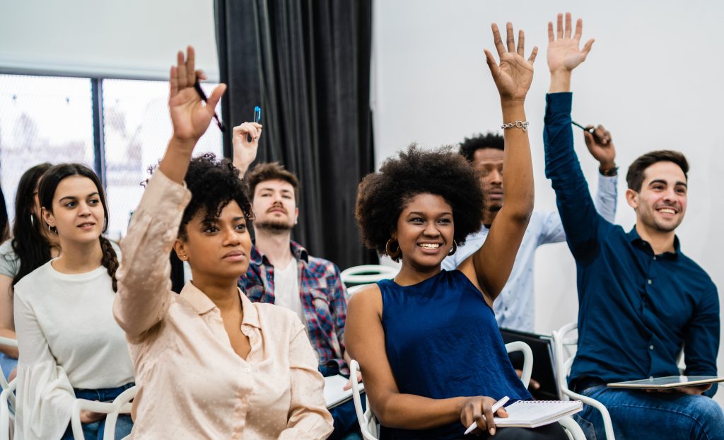 Group of students raising hands in a classroom